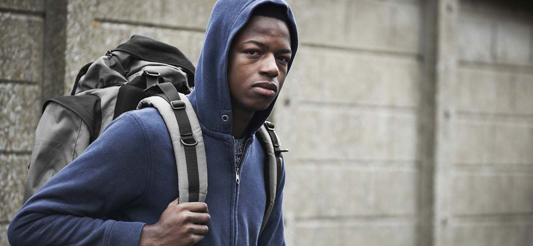 Young homeless person walking with backpack